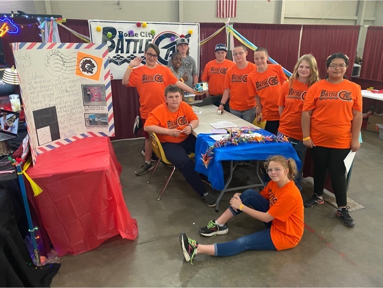The team pose at their booth with a large poster and colorful decorations.